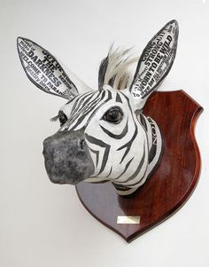 a zebra head mounted to the side of a wooden plaque with words on it's face