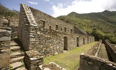 an old stone building sitting on top of a lush green hillside