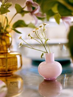 three vases filled with flowers sitting on top of a glass table next to each other