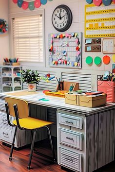 a desk with two yellow chairs and a clock on the wall above it in a classroom