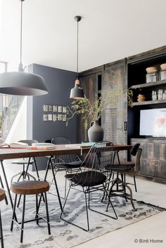 a dining room table with chairs and a television on the wall in the back ground