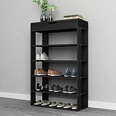 a black shelf with several pairs of shoes sitting on top of it next to a potted plant