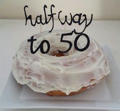 a frosted donut with candles on it sitting on a white plate that says halfway to 50