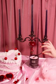 a pink table topped with a cake next to two candles and a pig figurine