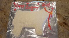 a cake shaped like a polar bear on top of a sheet of tin foil with red and white frosting