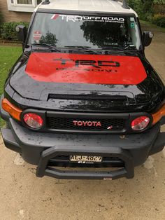 the front end of a black and red toyota fj cruiser parked on a driveway