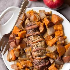 a white plate topped with meat and veggies next to two bowls of apples