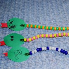 three plastic green and yellow snake necklaces on a blue background with white, orange, and red beads