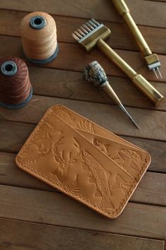 sewing supplies including thread, spools and scissors on a wooden table with a leather wallet