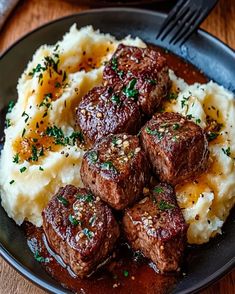 some meatballs and mashed potatoes on a plate with a fork next to it