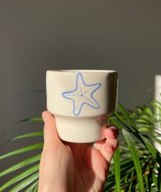 a hand holding a small bowl with a starfish painted on it