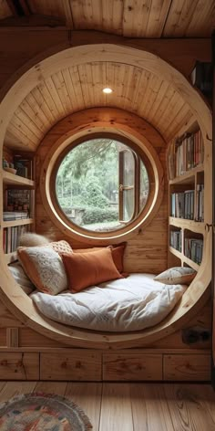 a room with a bed and bookshelves inside of it, in front of a round window