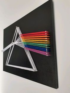 an art piece with colored pencils in the shape of a triangle on a black background