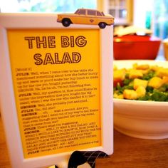 there is a sign that says the big salad in front of a bowl of salad