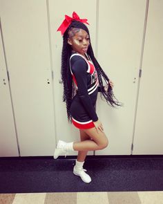 a girl in a cheerleader outfit leaning against a wall with her hands on her hips