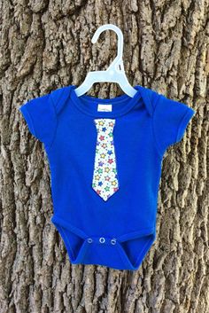 Hand decorated bodysuit.  This bodysuit features a tie on it.  Your little boy can look dressed up no matter the occasion! The tie decal is made from fabric and outlined with fabric paint.  Although pictured on a blue bodysuit, this would look adorable on any color!  I can create the tie with any color fabric - just ask! If you have any questions about this bodysuit, please let me know so I can assist you! Remember, as these items are handmade, each will be unique.  Although it may not arrive EX Fitted Blue Bodysuit For Spring, Spring Playtime Fitted Onesie, Blue Fitted Cotton Short Sleeve Bodysuit, Fitted Blue Short Sleeve Bodysuit For Playtime, Fitted Blue Bodysuit For Playtime, Playful Fitted Bodysuit For Playtime, Blue Fitted Bodysuit For Playtime, Cute Fitted Bodysuit For Playtime, Blue Fitted Short Sleeve Onesie