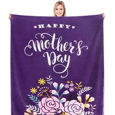 a woman holding up a purple towel with flowers and the words happy mother's day on it