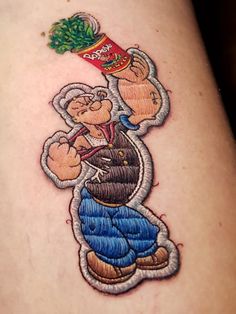 a person with a tattoo on their leg that has a cartoon character holding a can of ketchup