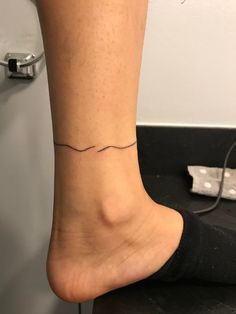 a woman's foot with a small wave tattoo on her left ankle and black socks