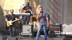 three men on stage singing and playing instruments