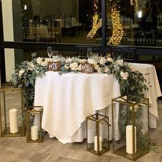 the table is set up with candles, flowers and greenery for an elegant wedding reception