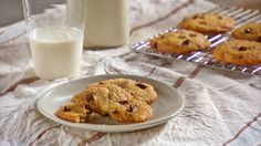 chocolate chip cookies on a plate next to a glass of milk and a cooling rack