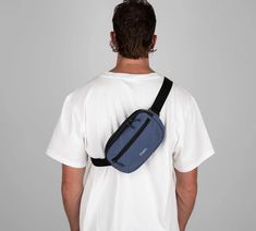 a man wearing a white t - shirt with a blue fanny bag on his back