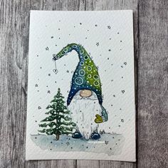 a card with an image of a gnome in the snow next to a christmas tree