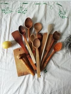 wooden spoons are lined up next to each other on a white cloth with green leaves