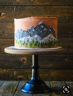 a cake with mountains on it sitting on top of a wooden table next to a wood wall