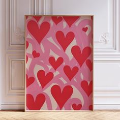 a red and white painting with hearts on it in front of a wall mounted art piece