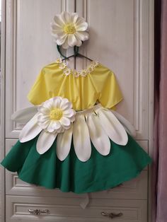 a dress made out of paper flowers hanging on a door