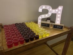 a wooden table topped with lots of cups and neon lights next to a sign that says 21st