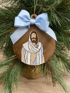 a wooden ornament with a blue bow hanging from it's side on a pine tree