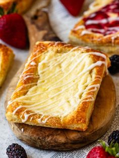 two slices of cheesecake sitting on top of a wooden cutting board next to berries