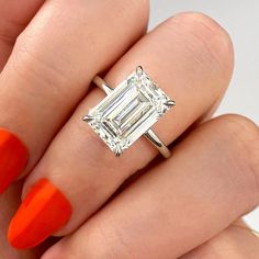 a woman's hand with an orange manicured nail polish holding a diamond ring