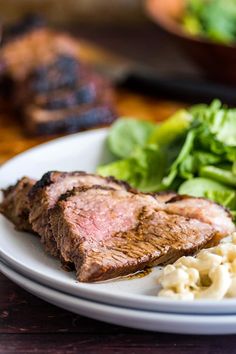 steak, macaroni and salad on a white plate with wooden table in the background