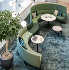 a green curved seating area in an office building with potted plants on the floor