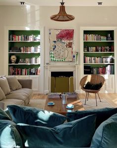 a living room filled with furniture and bookshelves next to a fire place under a painting