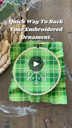 a green plaid cloth with an embroidered ornament on it next to a basket