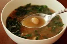 a white bowl filled with soup on top of a wooden table next to a spoon