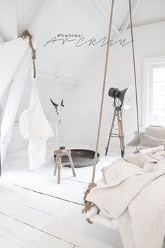 a bedroom with white walls and wooden floors, hanging clothes on the ropes in front of an open window