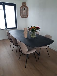 a dining room table with chairs and a vase filled with flowers next to a window