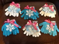 six pairs of gloves with bows and snowflakes on them sitting on a chair