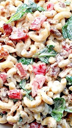 pasta salad with spinach and tomatoes in a white bowl