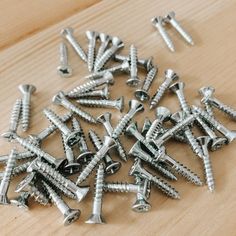 many screws are laying on a wooden surface