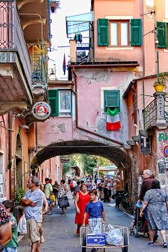 people are walking through an alleyway with shops and stores on either side, one person pushing a shopping cart down the street