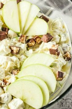 a glass bowl filled with apple slices and cream cheese salad on top of a table