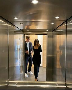 a man and woman walking through an elevator