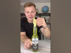 a man sitting at a table with a bottle of corona beer